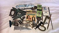 Full lot overview including eyeglasses, flashbulbs, locks, metal bird ornaments, small metal frame, and assorted tools and accessories
