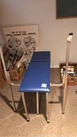 Front view of blue vinyl padded bench with steel frame and upright bar stands