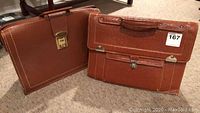 Front view of two brown leather briefcases, one with clasp lock and one with buckle closure and front pockets