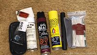 Full view of the lot on carpet, showing all items including lighter refills, lighter, pipe wipes, matches, and leather case.