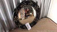 Front view of the vintage round hanging mirror with black and gold floral metal frame, showing overall design and size.