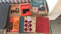 Lot of vintage and antique music books and sheets on a bench, various titles visible, some covers worn or damaged.