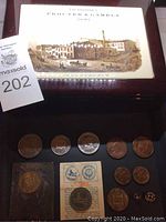 Top view of lacquered wooden box with Proctor and Gamble image on lid and assorted medallions placed on it