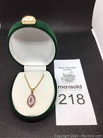 Green velvet presentation box open displaying necklace and pendant