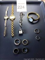 Full lot showing 4 watches and 6 rings arranged on black surface with lot number 224.