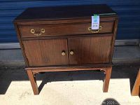 Front view of the wooden hutch showing the drawer and cabinet doors with brass handles and wooden knobs, standing on decorative legs.