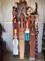 Four vintage wooden stand-up figures displayed side by side against a metal background, showing full front view.