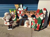 Group photo of all 13 Christmas decorations including Santa figure, wooden signs, framed art, and bowl