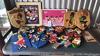 Overview of all 18 Disney character handmade wood decor pieces laid out on a table, showing various characters and colorful painted designs, some with minor damage.