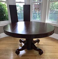 Full view of assembled 54-inch round table with two leaves propped behind