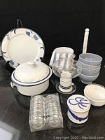 Photo showing Dansk casserole, four blue glazed bowls, marble paper towel holder, hurricane votive globe, white and blue patterned platter, ceramic spooner, towel, and butter bell clustered on counter.