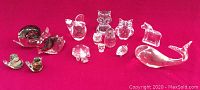 All crystal animal figurines laid out on red background showing full collection and variety of animal shapes and sizes.