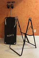 Full view of the assembled inversion table showing black padded backrest, metal frame, and stable A-frame design.