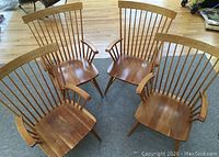 Four maple Windsor-style armchairs grouped together, showing angle and seating pods with armrests.