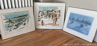 Three framed landscape prints leaning against a wall, all with cream mattes and silver-tone metal frames.