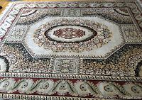 Full view of rug laid on hardwood floor showing central octagonal medallion and border