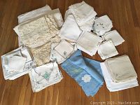 Overview of assorted linens, tablecloths, napkins, runners, and covers featuring embroidery and lace