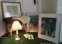 Overview photo of all items including ceramic base lamp with floral cut-paper shade, three framed prints, wooden bench, and two children's books.