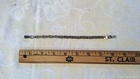 Full length view of the silver bracelet alongside a ruler showing measurement just under 8 inches.