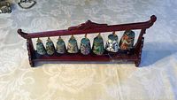 Full view of the cloisonne chimes displayed on the wooden rack showing all 8 bells in a single row with small hammer resting on the right side of the base.