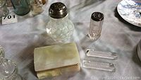 Lot view showing sugar shaker with metal shaker lid, marble rectangular hinged box, Victorian glass jar, and four crystal knife rests.