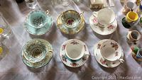 Photo of 4 pairs of fine bone china tea cups and saucers on a table, showing variety in colors and floral designs