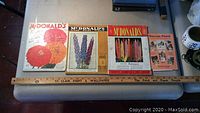 Photo showing four vintage seed and garden books from McDonald's including a 1932 garden book and 1940 seed catalogs on flowers and bulbs, laid out on a table.