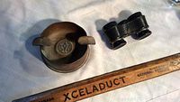 Photo of ash tray and binoculars next to ruler for scale