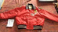 Full view of red Chicago Blackhawks jacket laid flat showing front, collar, sleeves, and ribbed detailing.