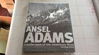 Front cover of the Ansel Adams photo book showing mountain range in black and white with title and author.