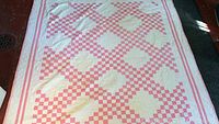 Top view of full quilt spread out on floor showing pink and white checkered pattern and overall design.