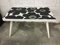 Front full view of white coffee table showing Marimekko black and grey floral patterned vinyl top.