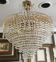Full view of large crystal chandelier showing shape, size, and overall design against ceiling and wall paintings
