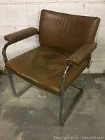 Front and side angle view of vintage chair showing brown leather seat and chrome cantilever frame with padded armrests.