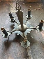 Top view of antique metal ceiling fixture showing five arms with bulb sockets and central figure.