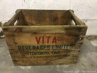 Wooden crate with VITA Beverages Limited, Toronto, ONT printed on side in red and green lettering with natural wood grain visible.