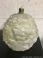 Front and side view of the vintage Mid Century Modern light globe, showing the textured translucent ruffled design and screw-in base.