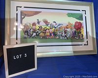 Front-facing photo of the framed Looney Tunes print showing most characters with gold-colored frame and chip visible.