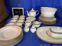 Full set arranged on blue cloth background, showing all cups, plates, bowls, and serving pieces.
