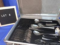 Open carry case showing organized compartments with multiple forks, knives, spoons, serving pieces in black foam lining.