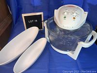 Full view of FlavorWave Turbo oven with two white porcelain serving dishes on blue background