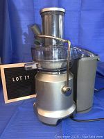 Front side view of silver Breville Juice Fountain Cold Juicer with feeding chute, pulp container, and power dial visible