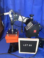 Full view of cap press machine with lever arm, orange 5x5 heating plate, and digital control unit on a blue background.