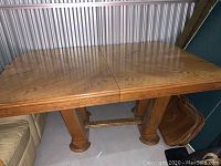 Wooden rectangular dining table with visible wood grain, no leaves inserted, with sturdy legs and crossbar.