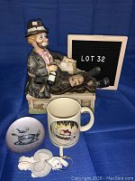 Full lot view showing musical hobo sculpture, angel bear ornament, plastic paperweight, and cartoon mug