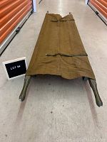 Canvas stretcher fully unfolded showing metal feet and straps on the canvas surface.