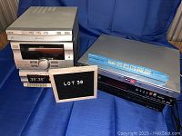 Full view of Sony RX33 stereo system next to two VHS/DVD recorders on blue cloth background with label showing lot number 36