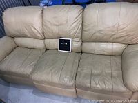 Full view of the cream-colored sectional sofa with three separate seats, showing wear and creases on the cushions and backrests.