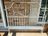 Headboard of the white steel queen size bed frame with decorative scrollwork.