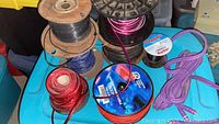 Overview of assorted speaker and electrical wires on spools and coils in different colors including red, purple, blue, black.